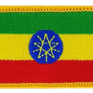 May include: An embroidered patch of the Ethiopian flag. The flag is green, yellow, and red with a blue circle in the center containing a yellow star with eight points.
