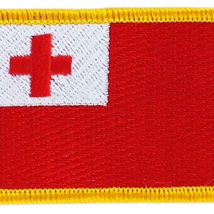 May include: A red and white embroidered patch with a yellow border. The patch features a white cross on a red background.