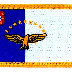 May include: A blue and white embroidered patch with a yellow border. The patch features a yellow bird with outstretched wings, a small blue and red shield, and a ring of yellow stars.