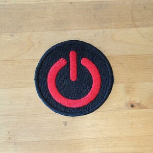May include: A black and red embroidered patch with a power button symbol.