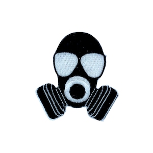 Puede incluir: Parche bordado en blanco y negro que representa una máscara de gas. El parche presenta una máscara de gas negra con lentes oculares blancos y un círculo blanco alrededor de la boca.