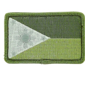 May include: A green and white embroidered patch with a white triangle and a circle in the center. The patch has a stitched border.