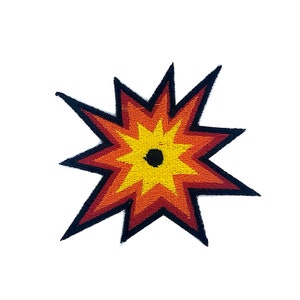 Op de afbeelding: Een geborduurde patch in de vorm van een ster met een zwart midden. De ster is rood en geel en heeft een stralend effect met meerdere punten.