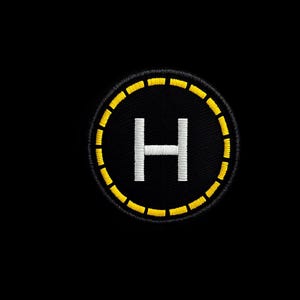 Könnte beinhalten: Gestickter Aufnäher mit einem schwarzen Kreis, einem gelben gestrichelten Rand und einem weißen "H" in der Mitte, das einen Hubschrauberlandeplatz darstellt. Zum Aufnähen auf Kleidung oder Ausrüstung.