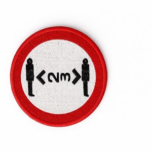 May include: Circular patch with a red border and a white centre. The patch shows black silhouettes of two people with an arrow and the text "<2m>" between them, indicating a social distancing guideline.