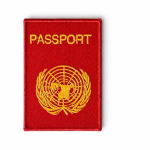 May include: A red passport patch with the word "PASSPORT" embroidered in gold. The patch features a gold emblem of a globe surrounded by a wreath. The patch is rectangular with a stitched border.