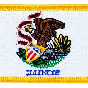 Op de afbeelding: Een witte patch met een gele rand met het staatszegel van Illinois. Het zegel toont een Amerikaanse zeearend met een schild op zijn borst, een opkomende zon boven een waterlichaam en de woorden "ILLINOIS" onderaan.