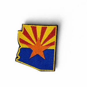 May include: Embroidered patch in the shape of Arizona, featuring the state flag design. The patch has a blue lower section, a yellow and red sunburst, and an orange star in the centre. The patch is outlined in black.