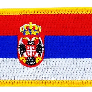 May include: A yellow embroidered patch with the flag of Serbia. The flag features three horizontal stripes of red, blue, and white with the Serbian coat of arms in the center.