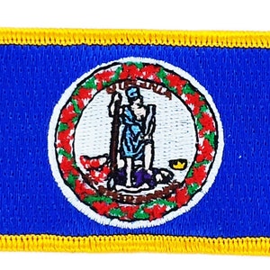 Könnte beinhalten: Ein gestickter Aufnäher in Blau und Gelb mit dem Staatssiegel von Virginia. Das Siegel zeigt eine Frau, die eine Lanze und einen Schild hält, umgeben von einem Kranz aus roten und grünen Blättern.