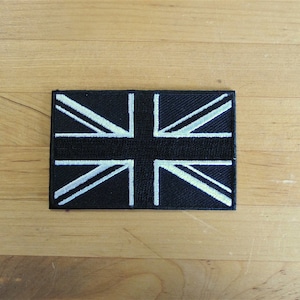 May include: Black embroidered patch with a white Union Jack flag design.