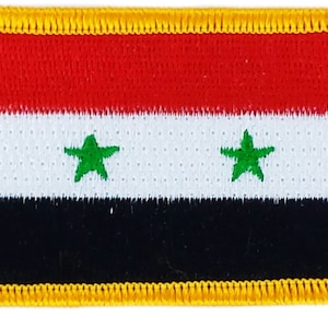 May include: A rectangular embroidered patch with a yellow border and the flag of Syria. The flag has three horizontal stripes: red, white, and black. The white stripe has two green five-pointed stars.
