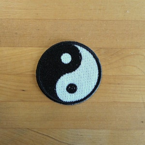 May include: A black and white yin yang symbol embroidered on a round patch.