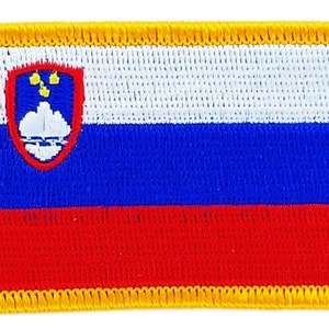 May include: A rectangular embroidered patch with the flag of Slovenia. The flag features three horizontal stripes of white, blue, and red, with the Slovenian coat of arms in the upper left corner. The patch is bordered with a yellow stitched trim.