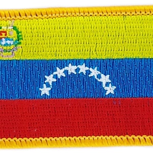 Könnte beinhalten: Ein gestickter Aufnäher der venezolanischen Flagge. Die Flagge ist gelb, blau und rot mit einem Wappen in der oberen linken Ecke und einer Reihe weißer Sterne im blauen Streifen.