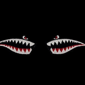 Può includere: Design ricamato di una bocca di squalo con affilati denti bianchi e dettagli rossi, su sfondo nero. Il design presenta due serie di denti e occhi rossi, creando un effetto visivo feroce e sorprendente.