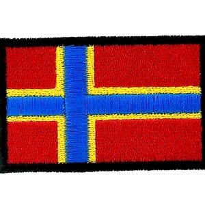 May include: Embroidered patch with a flag design. The patch has a red background with a blue cross outlined in yellow. The edges are black. Suitable for application on clothing or accessories.
