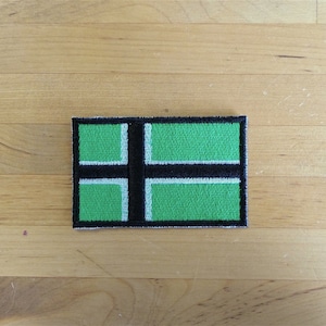 May include: An embroidered patch featuring a Scandinavian flag design in green and black.