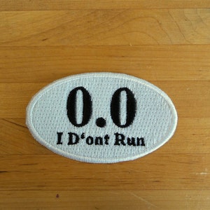 May include: White oval patch with black embroidery. The patch reads "0.0 I Don't Run".