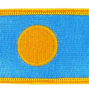 May include: A blue and yellow embroidered patch with a yellow circle in the center.