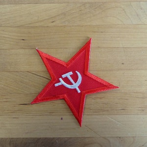 May include: A red five-pointed star with a white hammer and sickle symbol in the center.