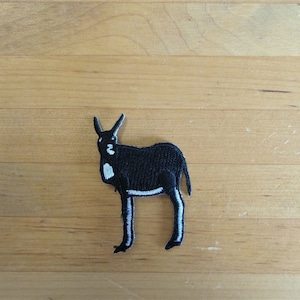 Puede incluir: Parche de planchado bordado en negro de un antílope negro con marcas blancas.