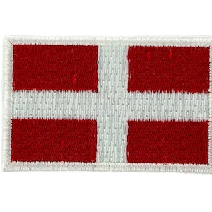 Może przedstawiać: Prostokątna naszywka z flagą Danii. Projekt zawiera biały krzyż skandynawski na czerwonym tle. Naszywka ma białą, haftowaną obwódkę.