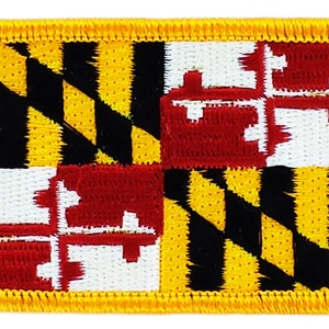 Könnte beinhalten: Ein gestickter Aufnäher mit der Flagge des Bundesstaates Maryland. Die Flagge ist gelb, schwarz und rot mit einem diagonalen Muster aus schwarzen und gelben Streifen und einem roten und weißen Wappen in der oberen rechten Ecke.