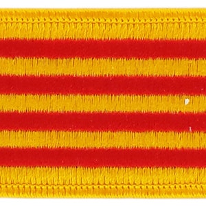 Puede incluir: Un parche bordado de color amarillo y rojo con forma rectangular y borde amarillo. El parche presenta cuatro franjas horizontales rojas que se alternan con cuatro franjas horizontales amarillas.