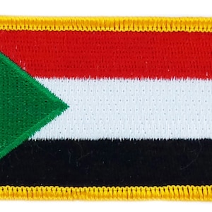 May include: Embroidered patch depicting the flag of Sudan. The rectangular patch features a red stripe, a white stripe, and a black stripe. A green triangle is positioned on the left side, with a gold border.