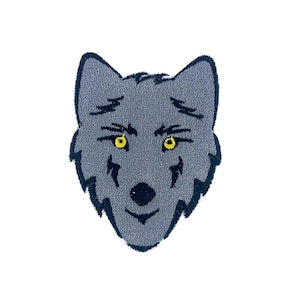 Puede incluir: Un parche bordado de cabeza de lobo gris con contornos negros y ojos amarillos.