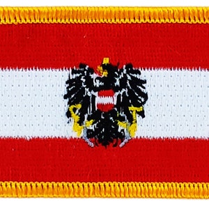 May include: A red, white, and red Austrian flag patch with a black eagle and coat of arms in the center. The patch has a yellow border.