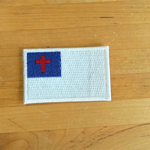 Può includere: Toppa ricamata bianca con un design di bandiera cristiana blu e rossa. La bandiera presenta una croce bianca su sfondo blu.