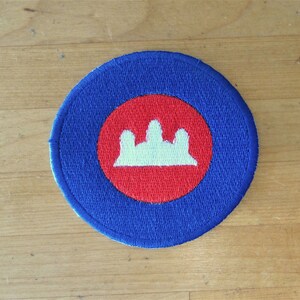May include: A blue and red circular patch with a white crown design in the center.