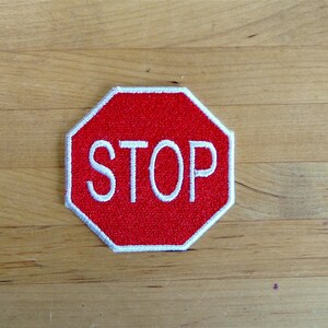 Pode incluir: Sinal de parada octogonal vermelho com borda branca e texto branco que diz "STOP".