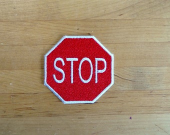 Könnte beinhalten: Ein rotes achteckiges Stoppschild mit weißem Rand und weißem Text, der "STOP" lautet.