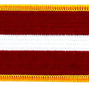 May include: Embroidered patch featuring the flag of Latvia. The rectangular patch has a maroon background with a white horizontal stripe in the center. The border is a gold-colored, decorative stitch.