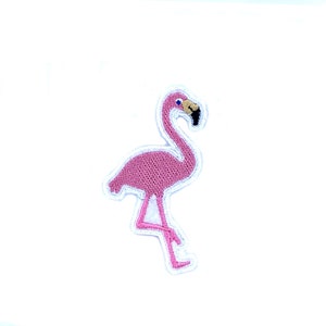 以下が含まれることがあります： ピンクのフラミンゴの刺繍アイロン接着パッチ。フラミンゴは片足で立っており、頭を下げています。