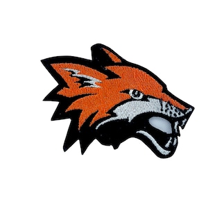 May include: An orange and black embroidered patch of a fox's head with a white mouth and teeth.