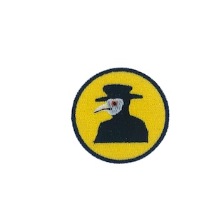 Puede incluir: Un círculo amarillo con un contorno negro presenta una silueta negra de un médico de la peste que lleva una larga túnica negra, un sombrero de ala ancha y una máscara de pico largo.