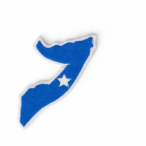 May include: A blue embroidered patch in the shape of the Somalia map. The patch has a white border and a white star in the center. The background is white.