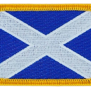 Könnte beinhalten: Ein blauer und weißer gestickter Aufnäher mit einem weißen Kreuz auf blauem Hintergrund. Der Aufnäher hat einen gelben Rand.