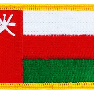 Pode incluir: Um remendo bordado vermelho, branco e verde com uma borda dourada. O remendo apresenta um símbolo branco de espadas cruzadas com uma estrela no centro.