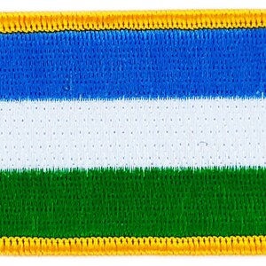 Könnte beinhalten: Eine rechteckige Flagge in Blau, Weiß und Grün mit gelbem Rand. Die Flagge ist aus Stoff und hat eine strukturierte Oberfläche.