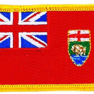 May include: A red embroidered patch with a gold border, featuring the Union Jack in the upper left corner and a coat of arms in the upper right corner. The coat of arms is green, blue, and white with a red cross and a white bear.