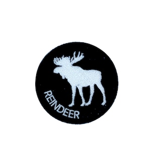 May include: A black circular patch with a white embroidered reindeer silhouette and the word "REINDEER" written in a white arc below the reindeer.