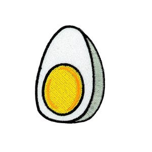 Op de afbeelding: Geborduurde patch met een cartoon hardgekookt ei. Het ei heeft een witte buitenlaag, een gele dooier en een zwarte omtrek. De patch is ontworpen voor toepassing op kleding of accessoires.