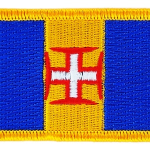 Puede incluir: Un parche bordado azul y amarillo con el escudo de armas de Portugal en el centro. El escudo de armas es una cruz blanca sobre un escudo rojo.