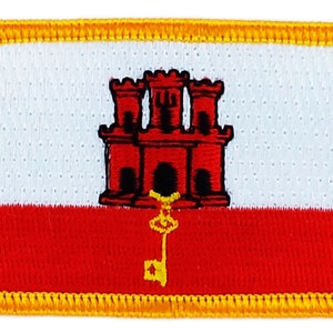 Op de afbeelding: Een geborduurde patch met het wapen van Gibraltar. Het wapen is rood, wit en geel en toont een rood kasteel met drie torens en een gouden sleutel.