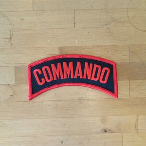 May include: Black patch with red embroidered text that reads "COMMANDO".
